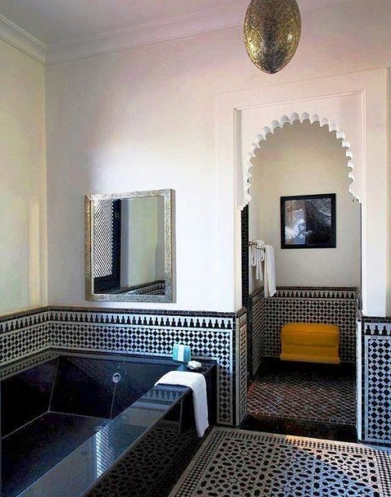 a navy and white bathroom with plaster and tile walls and floor, a tiled bathtub and a pendant lamp