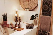 a neutral bathroom with a decorative tray, potted greenery and candles, a ladder with printed towels and a jute rug