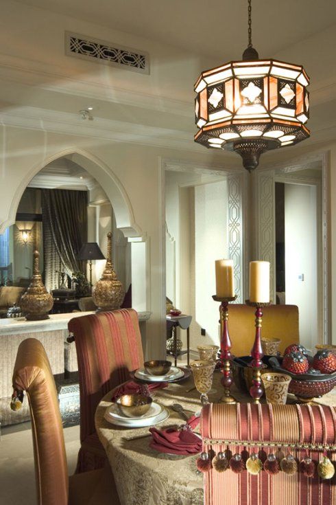 a neutral dining room with mismatching chairs, a beautiful pendant lamp and tassels and pompoms, candles in the center of the table