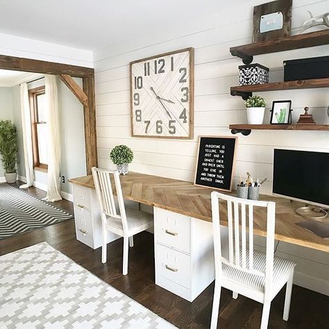 a neutral farmhouse home office with a shared desk, white chairs, open shelves, a large clock and greenery