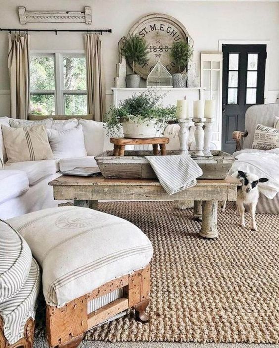 a neutral rustic living room with rough wooden tables, a stool, some whitewashed candleholders and a jute rug