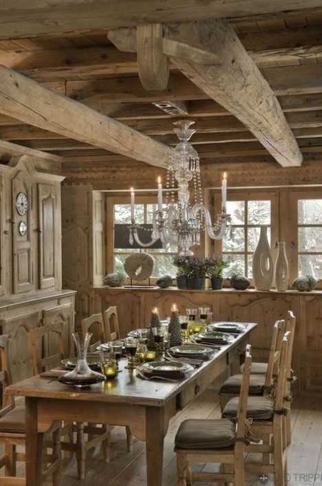 a rustic chalet dining space all done with wood, with vintage carved furniture, a crystal chandelier and some candles