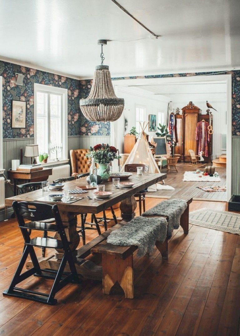 a rustic dining space with a Moroccan feel, a wooden table, benches and chairs, a leather chair and floral wallpaper