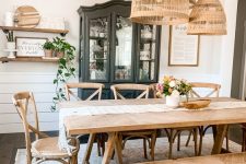 a rustic dining space with a black storage unit, a stained wooden table and a bench, lovely stained chairs and a cluster of pendant lamps