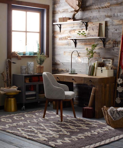 a rustic home office with a salvaged wooden wall, a wooden desk and a metal cabinet, some open shleves and a striped chair