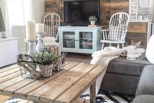 a rustic living room with a reclaimed wood wall, a wooden table, grey and blue furniture and refined vintage chairs