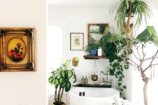 a small boho bathroom with a soak tub, a boho rug, potted greenery and artworks