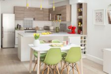 a stylish contemporary kitchen with wooden and white cbainets, with yellow bulbs, green chairs and some yellow touches