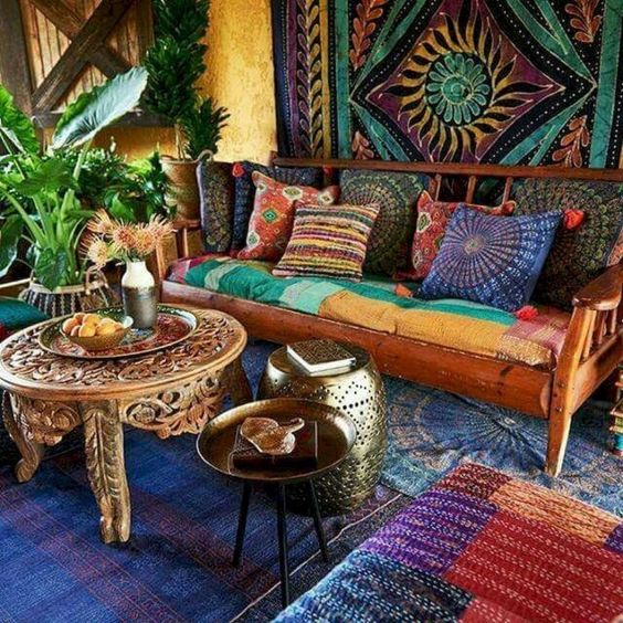 a super colorful living room with carved furniture, colorful textiles and potted plants here and there