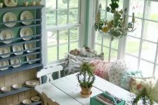 a sweet vintage dining room with mint walls, a white vintage dining set, a blue shelving unit and a cool vintage chandelier