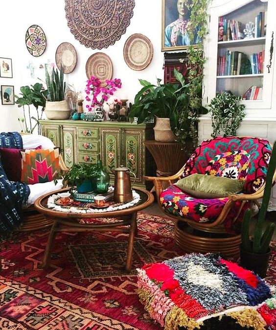 a very bright living room with colorful rugs, cushions and pillows, baskets on the wall and painted furniture