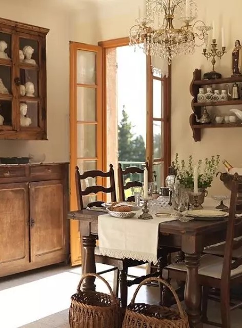 a vintage farmhouse dining room with stained furniture   a dining set, a wall mounted shelf and some cabinets, a crystal chandelier