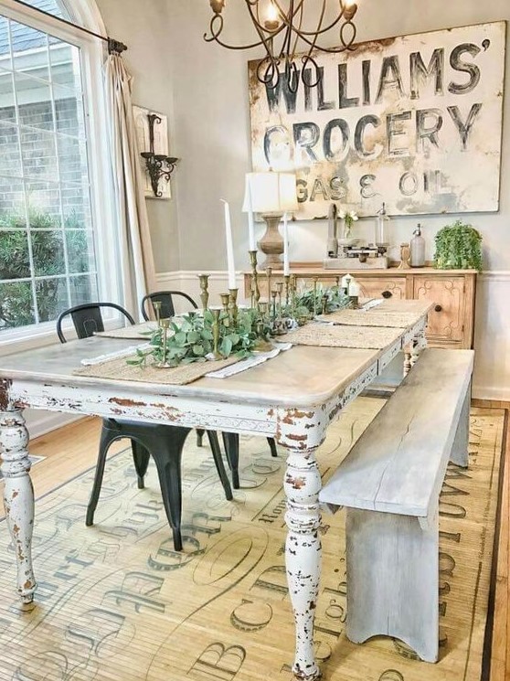 a vintage farmhouse dining space with a large sign, a wooden buffet, a shabby chic table and whitewashed bench
