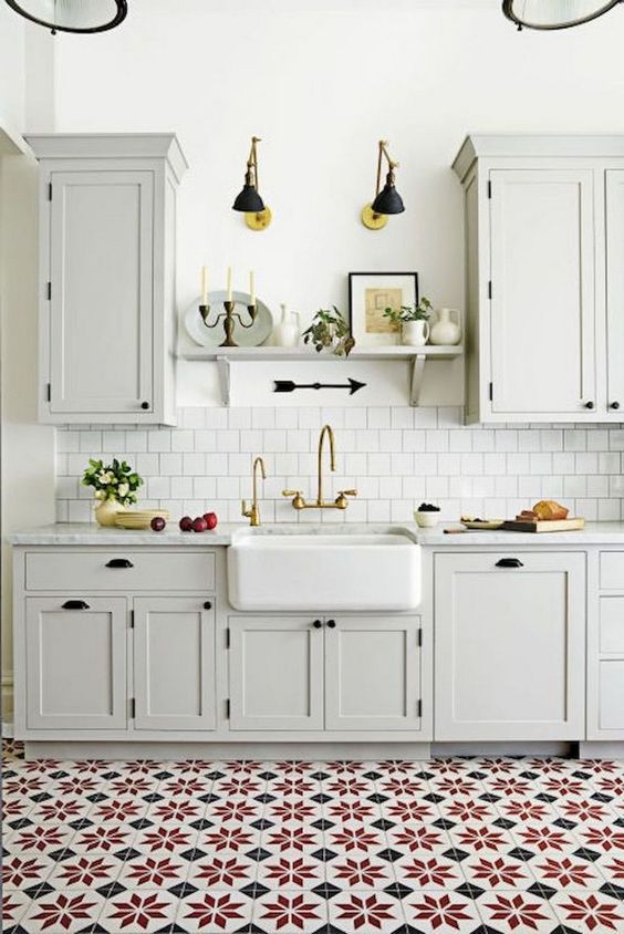 a vintage neutral kitchen with elegant cabinets, a white tile backsplash, a colorful tile floor and black wall lamps