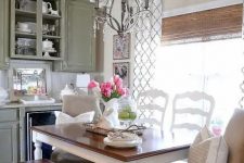 a vintage rustic dining space with a table with a stained tabletop, benches and matching white chairs, a lovely pendant lamp