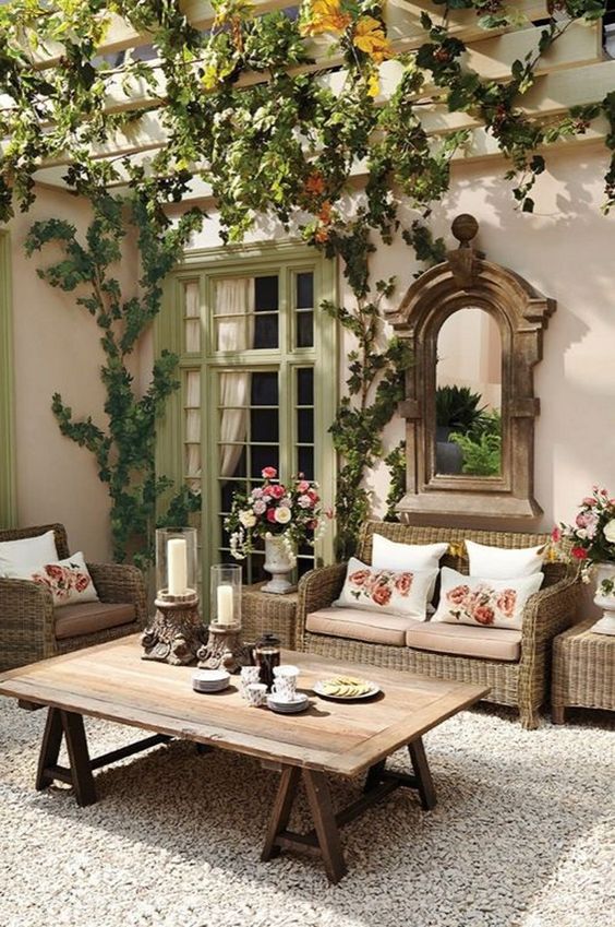 a welcoming rustic patio with wicker and wooden furniture, lot sof vines and a vintage mirror in a wooden frame