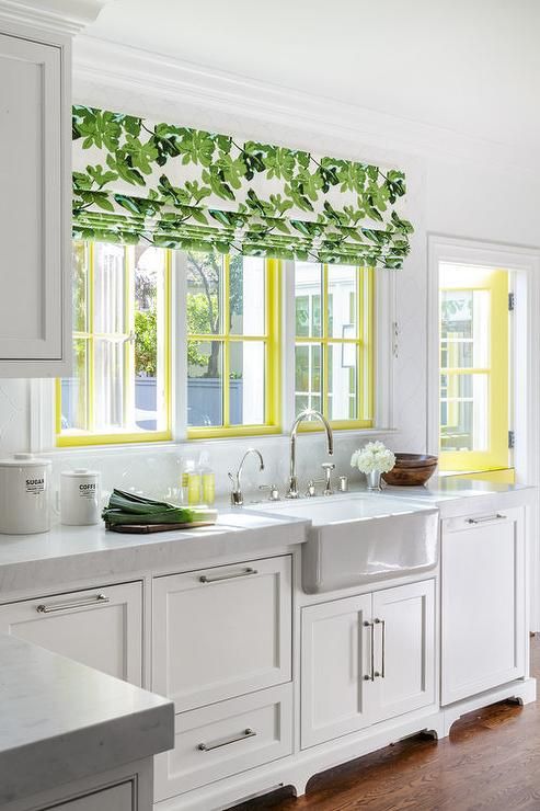 a white cottage kitchen with a yellow frame window and a botanical print curtain plus a yellow door