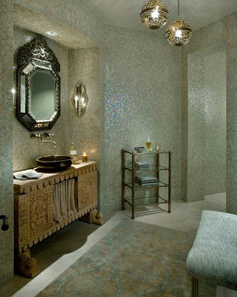 a mother-of-pearl bathroom with a carved wooden vanity, an ornated mirror and some pendant lamps  (Nance Construction)