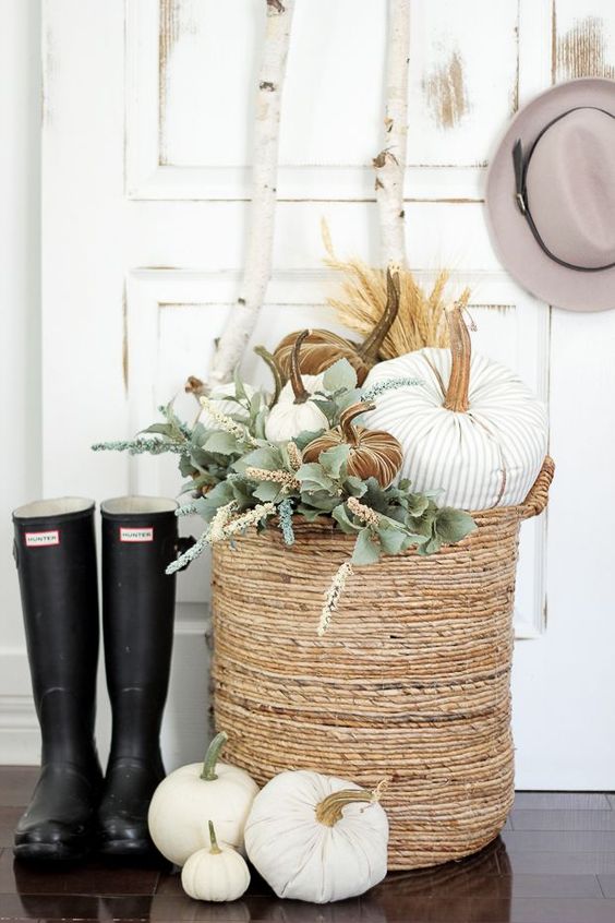 a basket with white, striped and rust velvet pumpkins and greenery plus rubber boots for cool fall decor