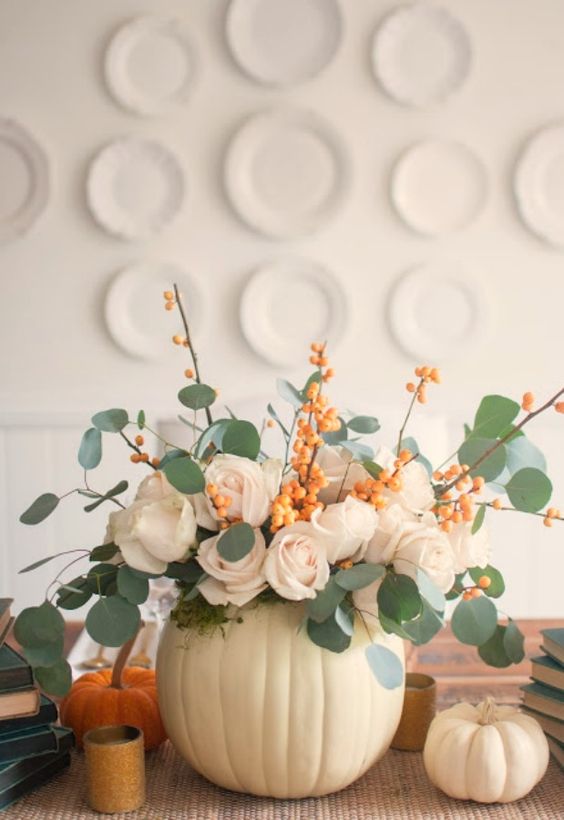 a beautiful and easy fall centerpiece of a white pumpkin, blush roses, eucalyptus and branches with berries