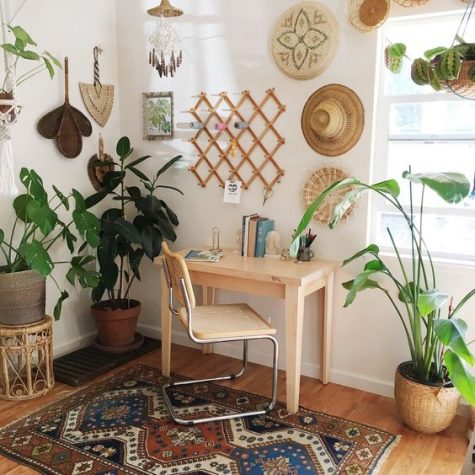 a boho home office nook with hats and decorative baskets, potted plants, a boho rug, a simple desk and a leather chair