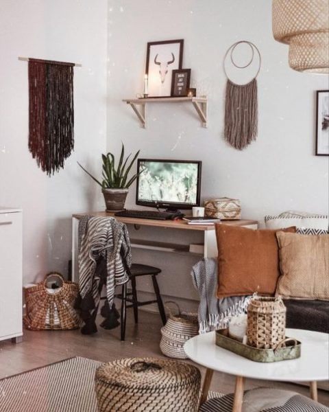 a boho home office with long fringe hanging, a sleek desk, lots of basket for storage and earthy tone pillows