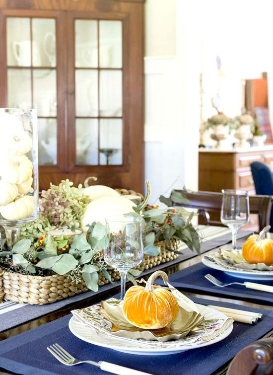 a bold fall table setting with mustard velvet pumpkins and a chic centerpiece of a woven basket with eucalyptus and berries
