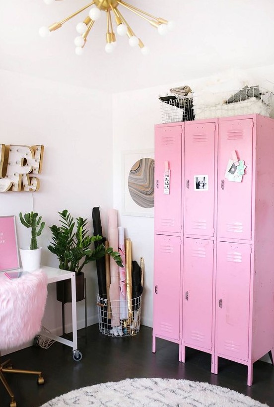 a bold glam feminine home office with pink furniture and art, a gold burst chandelier and potted plants