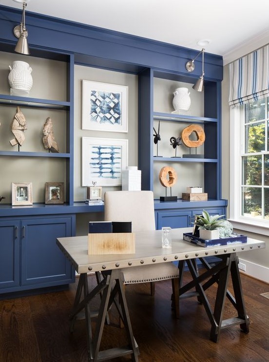 a bright blue home office with a large storage unit that takes a whole wall, a white industrial desk, a white chair and striped curtains