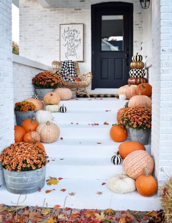a bright fall to Halloween porch with various pumpkins, black and white ones and bright fall blooms
