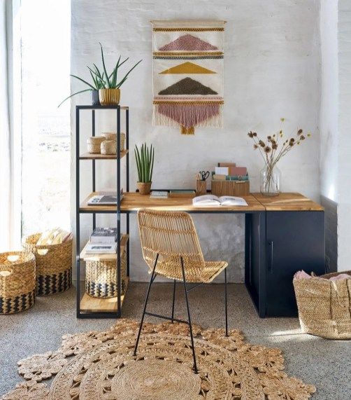a bright home office with a navy desk, a rattan chair, a jute rug, baskets, a bright wall hanging and an open shelf