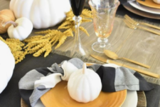 a contrasting fall tablescape with printed textiles, black glasses, wheat, white pumpkins and gold cutlery