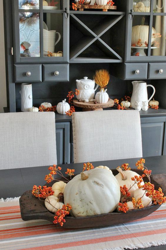 un bol de pâte avec des baies et des citrouilles blanches, et décor similaire sur le buffet derrière un bol de pâte avec des baies et des citrouilles blanches, et décor similaire sur le buffet derrière