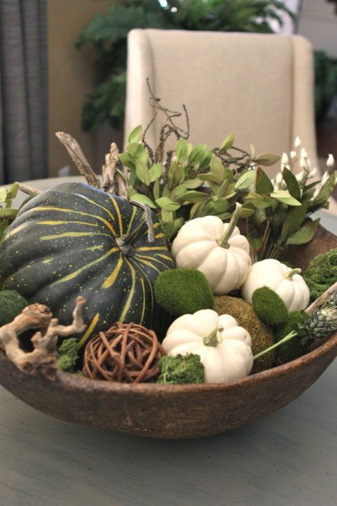 a dough bowl with moss, pumpkins and gourds, foliage, driftwood for a simple rustic fall centerpiece