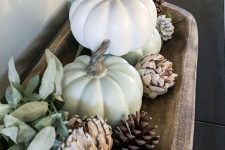 a dough bowl with pinecones, greenery balls, pumpkins and pale greenery is a lovely and easy fall centerpiece