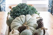 a dough bowl with pumpkins and gourds, pinecones and cabbage is a rustic and relaxed centerpiece for the fall