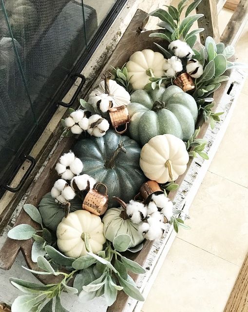 a dough bowl with pumpkins, real and faux ones, cotton, greenery and copper mugs is a chic and stylish arrangement to decorate a space