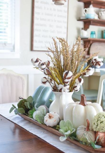 une pièce maîtresse d'automne avec de fausses citrouilles, de la verdure, des plantes succulentes, des herbes et du coton dans une simple cruche blanche une pièce maîtresse d'automne avec de fausses citrouilles, de la verdure, des plantes succulentes, des herbes et du coton dans une simple cruche blanche