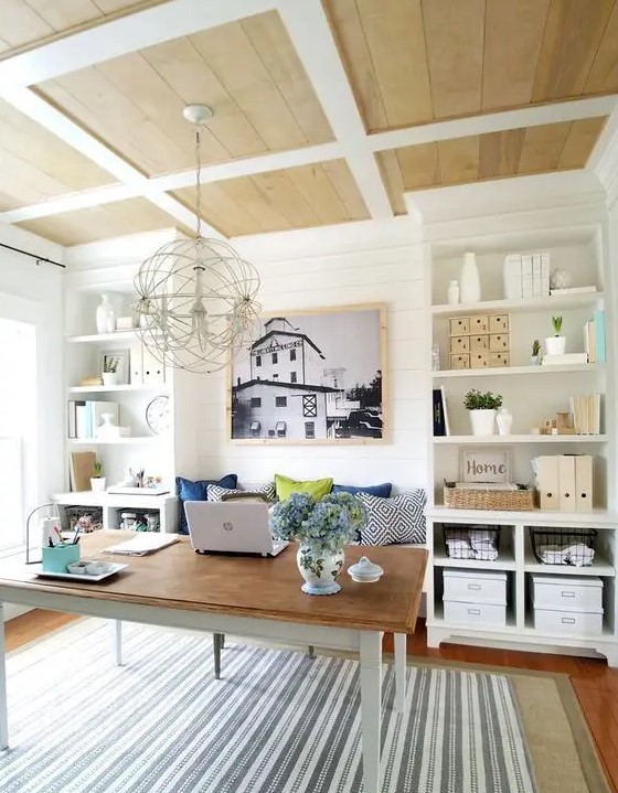 a farmhouse home office with built-in storage units, a simple desk and a built-in bench to sit on, a sphere chandelier