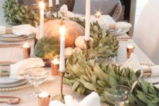 a gorgeous fall table runner of greenery, natural pumpkins and white candles