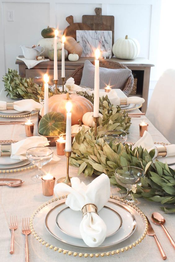 a gorgeous fall table runner of greenery, natural pumpkins and white candles