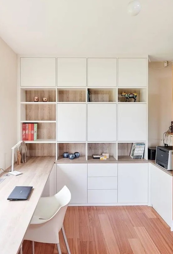 a minimalist home office with white and stained storage units, with a built-in desk and some pretty decor is very chic