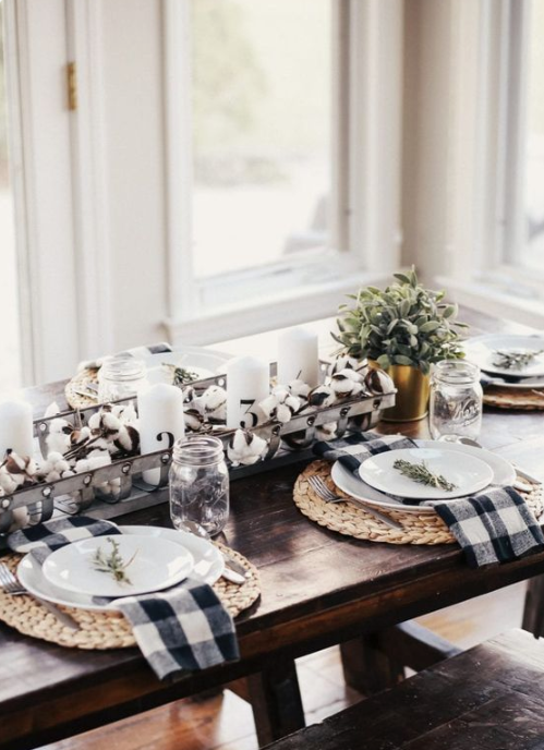 a monochromatic farmhouse tablescape with woven placemats, plaid napkins, a cotton and candle centerpiece plus greenery in a pot