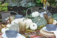 a natural fall table with a plaid tablecloth, wood slice placemats, natural pumpkins, herbs and a billy ball centerpiece