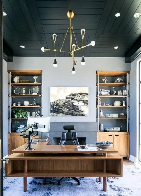 a refined beach home office with grey walls, a black wooden ceiling, built-in storage units and a large stained desk plus a sea-inspired rug