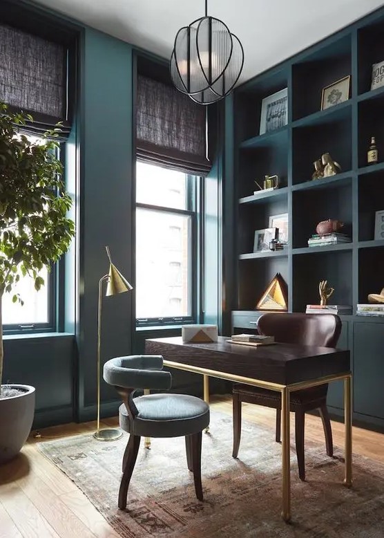 مكاتب منزلية A-refined-teal-home-office-with-a-built-in-storage-unit-a-dark-stained-desk-and-a-brown-chair-a-grey-chair-and-gilded-touches