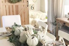 a relaxed neutral fall centerpiece of pale greenery, neutral pumpkins and wax flowers is a cool idea for your tablescape