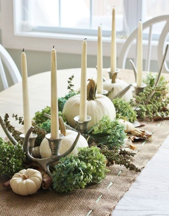 a rustic fall centerpiece of burlap, green hydrangeas, white pumpkins, antlers and tall candles is cozy and stylish