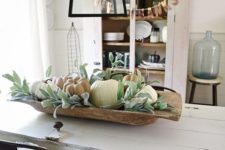 a simple rustic fall centerpiece of a dough bowl, greenery and neutral pumpkins will bring a fall feel to the space