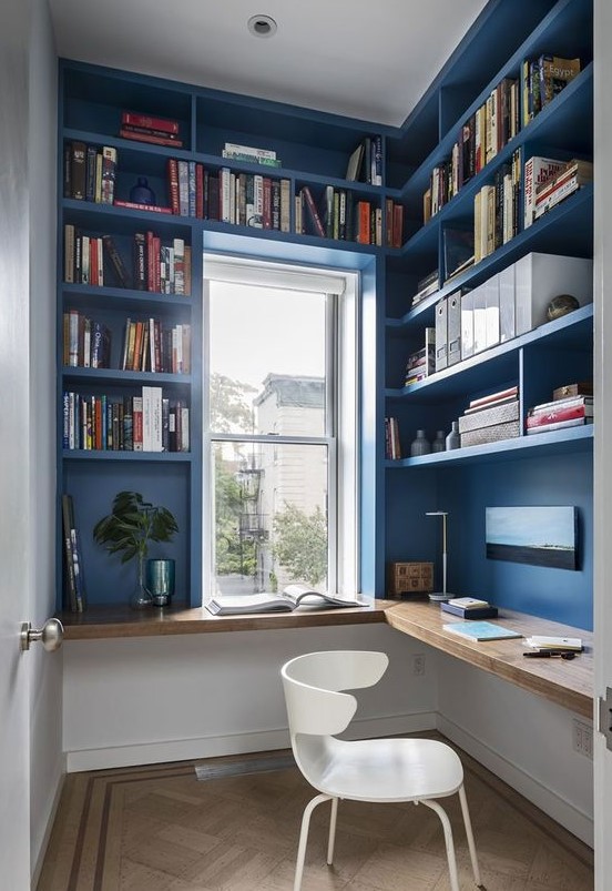 a small and bright home office, all the walls are taken by storage unit, a floating desk and a white chair